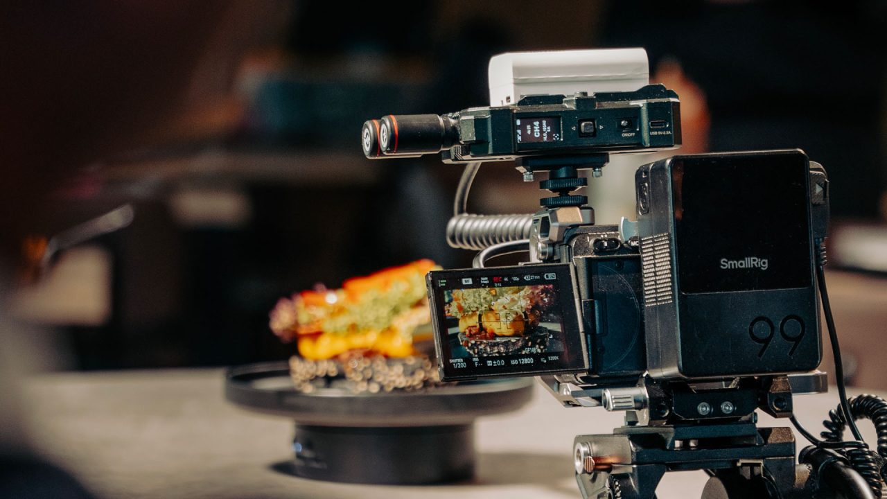 Cinema rig su un tavolo da set food: sullo schermo della camera il piatto con il REC rosso acceso